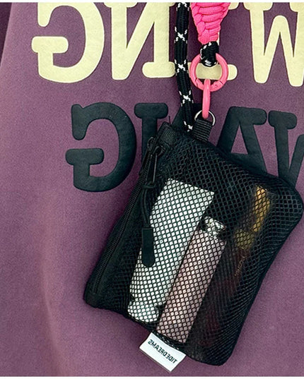 Black mesh makeup bag with pink strap hanging from a purple hoodie, coin purse, lip balm storage