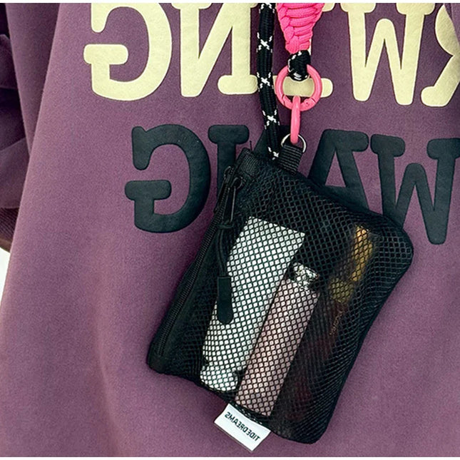 Black mesh makeup bag with pink strap hanging from a purple hoodie, coin purse, lip balm storage